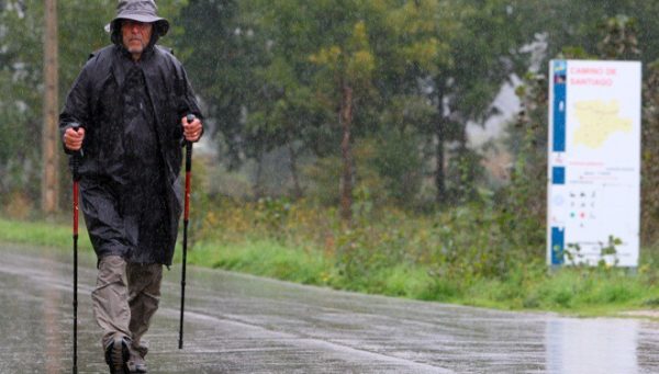 Un peregrino camina bajo la lluvia a su paso por Ponferrada (César Sánchez)