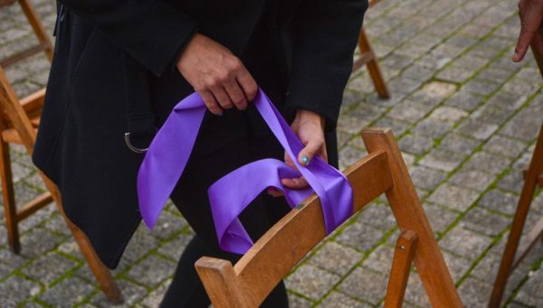 Una mujer pone un lazo en una de las sillas vacías usadas en Ponferrada para recordar a las víctimas de la violencia de género el pasado 25 de noviembre. / QUINITO