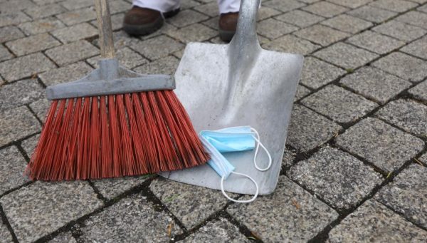 Un trabajador de la limpieza retira una mascarilla de la calle