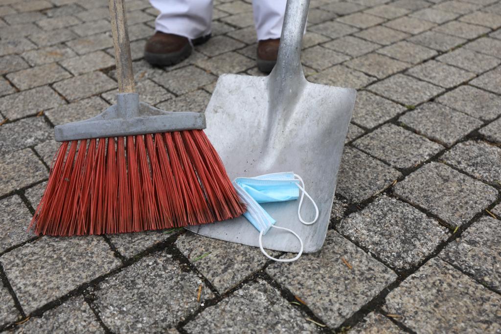 Un trabajador de la limpieza retira una mascarilla de la calle