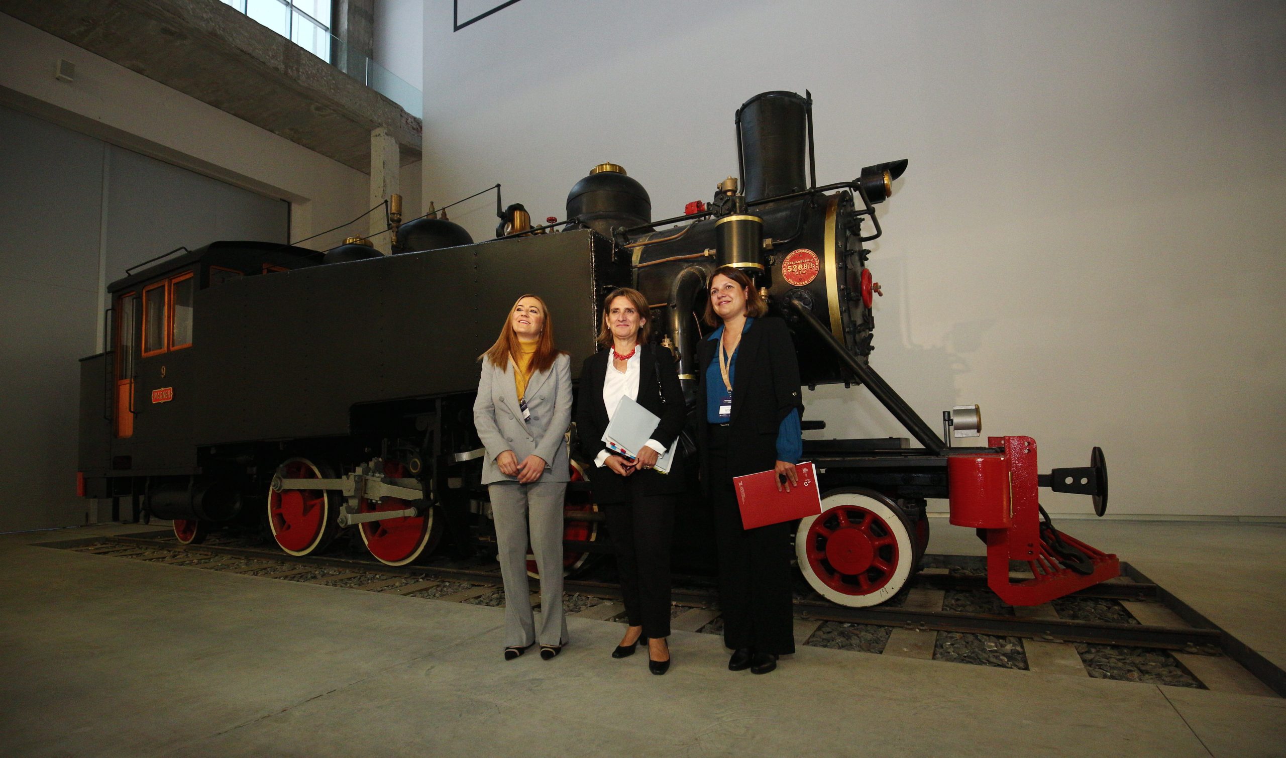 Virginia Barcones, Teresa Ribera y Yasodhara López, ante una de las locomotoras del Ponfeblino