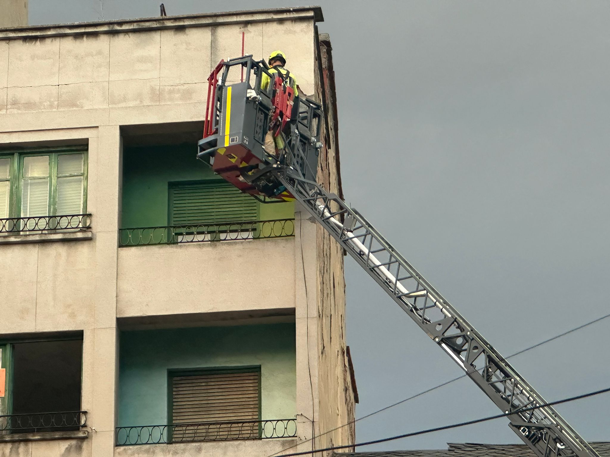 Los bomberos trabajan en la retirada de cascotes de un edificio de la avenida de la Puebla