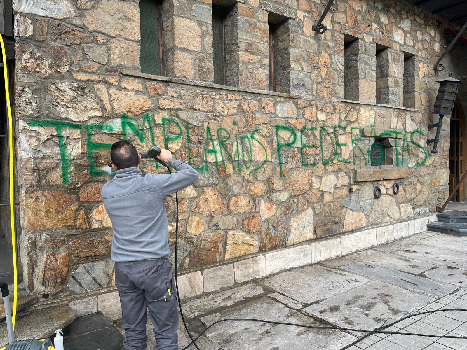 Un operario limpia la pintada en la fachada del hotel Temple